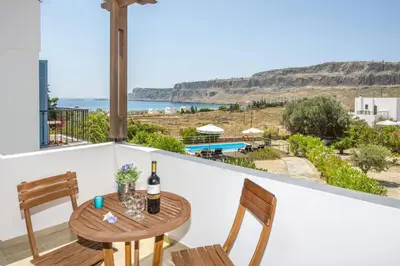 a table with two chairs and a bottle of wine on a balcony at Villa Aqua Blu by Villa Plus in Líndos