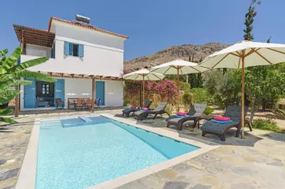 a villa with a swimming pool with chairs and umbrellas at Villa Aqua Maris by Villa Plus in Líndos
