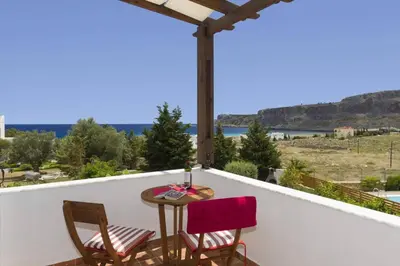 a table and chairs on a balcony with a view of the ocean at Villa Aqua Maris by Villa Plus in Líndos