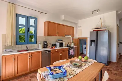 a kitchen with a table and a stainless steel refrigerator at Villa Aqua Maris by Villa Plus in Líndos