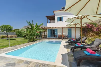 a villa with a swimming pool with chairs and umbrellas at Villa Aqua Maris by Villa Plus in Líndos