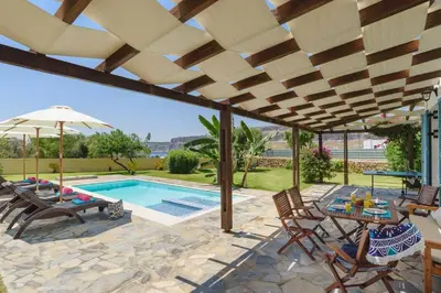 a patio with a pool and chairs and an umbrella at Villa Aqua Maris by Villa Plus in Líndos