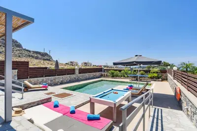 a backyard pool with a pool table and an umbrella at Villa Beatris Seastone by Villa Plus in Kiotari
