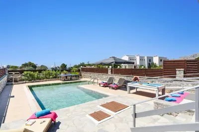 a swimming pool with chaise lounges and a pool table at Villa Beatris Seastone by Villa Plus in Kiotari