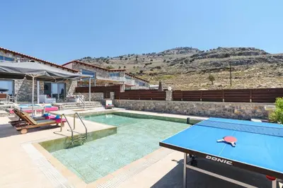 a pool with a ping pong table next to a house at Villa Beatris Seastone by Villa Plus in Kiotari