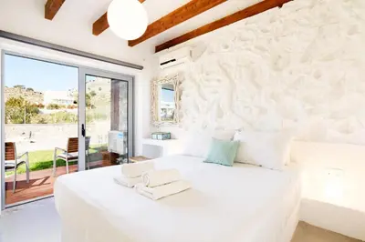 a bedroom with a white bed and a large window at Villa Beatris Seastone by Villa Plus in Kiotari