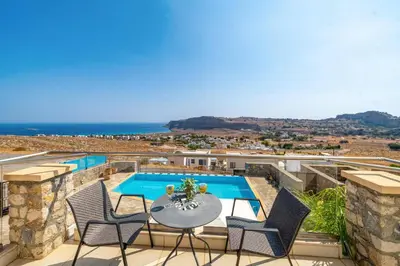 a patio with a table and chairs and a swimming pool at Villa Castello by Villa Plus in Líndos