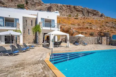 a villa with a swimming pool next to a mountain at Villa Castello by Villa Plus in Líndos