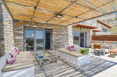 a patio with a couch and a table at Villa Chloe Seastone by Villa Plus in Kiotari