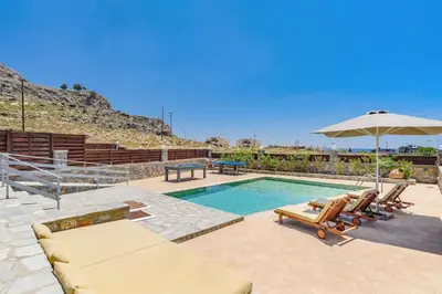 a swimming pool with two lounge chairs and an umbrella at Villa Chloe Seastone by Villa Plus in Kiotari
