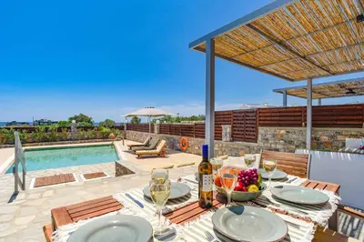 a table with wine glasses and a bowl of fruit on a patio at Villa Chloe Seastone by Villa Plus in Kiotari