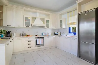 a kitchen with white cabinets and a stainless steel refrigerator at Villa Christina Rhodes by Villa Plus in Líndos
