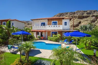 a villa with a swimming pool and blue umbrellas at Villa Christina Rhodes by Villa Plus in Líndos