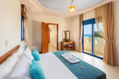 a bedroom with a large white bed with blue pillows at Villa Clive by Villa Plus in Líndos