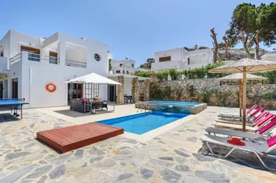 a villa with a swimming pool with chairs and umbrellas at Villa Despina by Villa Plus in Pefki Rhodes