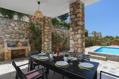 a table and chairs with a table and a swimming pool at Villa Despina by Villa Plus in Pefki Rhodes