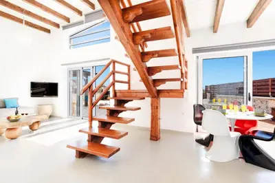 a wooden spiral staircase in a living room with a table at Villa Dione Seastone by Villa Plus in Kiotari