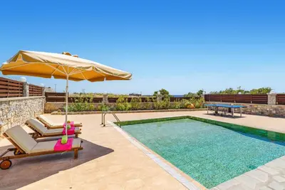 a pool with a chair and an umbrella and a table at Villa Dione Seastone by Villa Plus in Kiotari