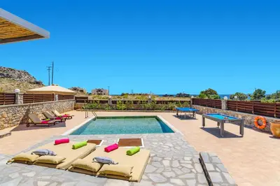 a swimming pool with chaise lounge chairs and a pool table at Villa Dione Seastone by Villa Plus in Kiotari