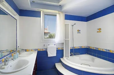 a blue and white bathroom with two sinks and a tub at Villa Helios Rodos by Villa Plus in Asgourou