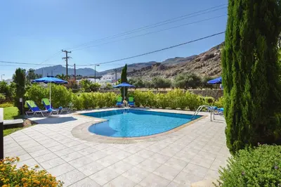 a swimming pool in a yard with chairs and umbrellas at Villa Matina by Villa Plus in Líndos