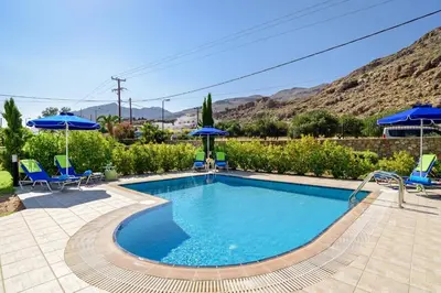 a swimming pool with blue chairs and umbrellas at Villa Matina by Villa Plus in Líndos