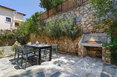 a table and chairs and a stone wall with a fireplace at Villa Maya by Villa Plus in Pefki Rhodes