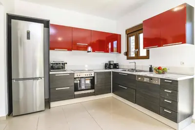 a kitchen with red cabinets and a stainless steel refrigerator at Villa Maya by Villa Plus in Pefki Rhodes