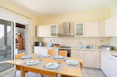 a kitchen with a wooden table with chairs and a table and a table at Villa Selini by Villa Plus in Pefki Rhodes