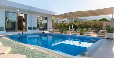 a swimming pool in a house with chairs and an umbrella at Villa Gaia Green-Adults only in Kolimbia