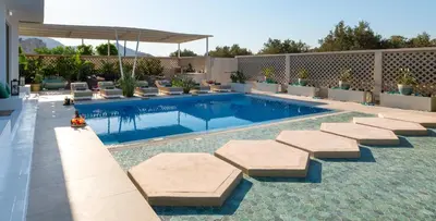 a swimming pool with cushioned chairs and a swimming poolvisor at Villa Gaia Green-Adults only in Kolimbia