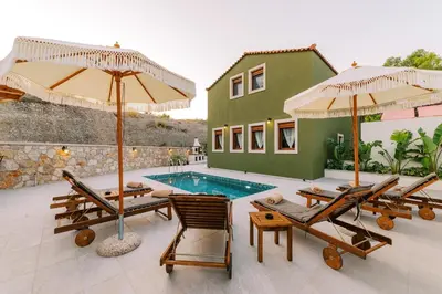 a villa with a swimming pool with chairs and umbrellas at Stavlos Luxury Stone House in Ialyssos