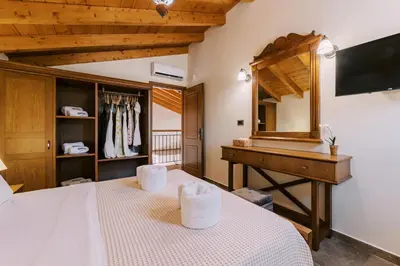 a bedroom with a bed and a dresser and a mirror at Stavlos Luxury Stone House in Ialyssos