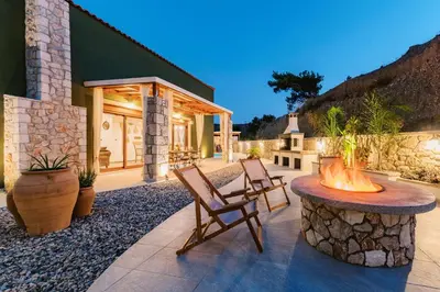 a patio with two chairs and a fire pit at Stavlos Luxury Stone House in Ialyssos
