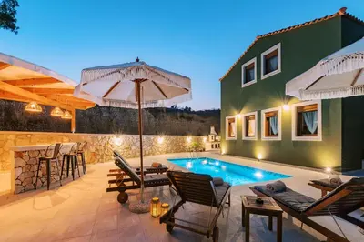 a patio with a pool and chairs and an umbrella at Stavlos Luxury Stone House in Ialyssos