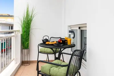 a table on a balcony with a drink on it at Port Living Apartments in Rhodes Town