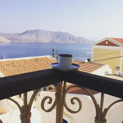 a cup of coffee sitting on the ledge of a balcony at Kleopatra Sweet Home in Symi