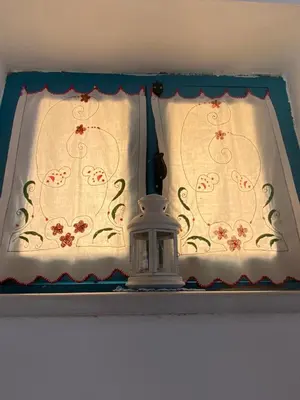 a window with a white curtain and a lantern at Kleopatra Sweet Home in Symi