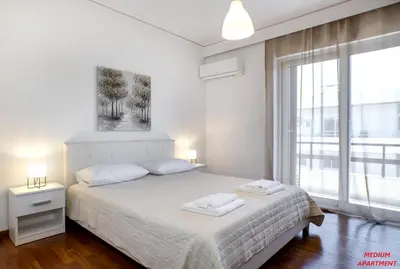 a white bedroom with a bed and a large window at Rhodes Heart Apartments close to the old town in Rhodes Town