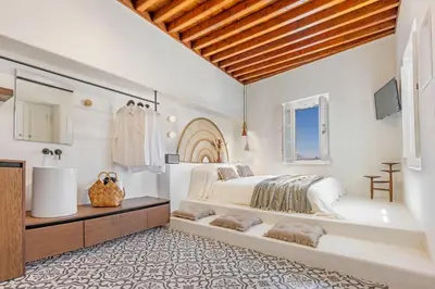 a bedroom with a large bed and a tub at Peni sol Superior Studios Lindos in Líndos