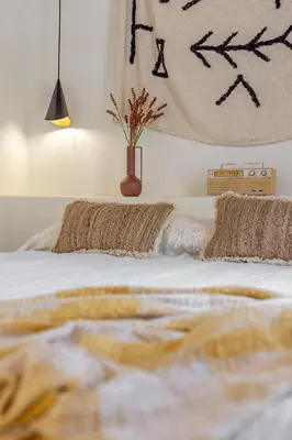 a bed with two pillows and a vase on it at Peni sol Superior Studios Lindos in Líndos