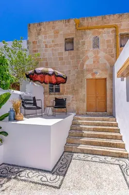 a patio with a table and an umbrella at Peni sol Superior Studios Lindos in Líndos