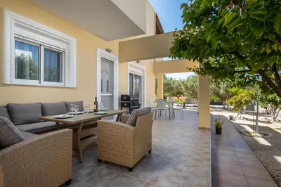 a patio with a wooden table and chairs at Sunny Garden Apartments in Pastida