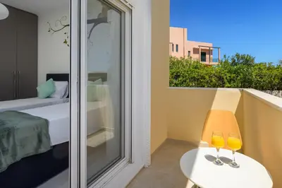 a room with a balcony with two wine glasses on a table at Sunny Garden Apartments in Pastida