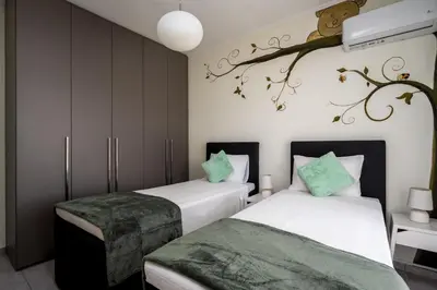 a bedroom with two beds and a branch on the wall at Sunny Garden Apartments in Pastida