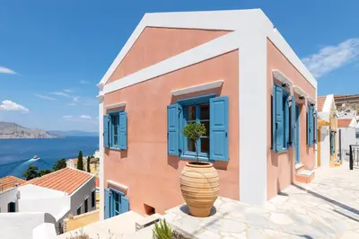 a building with blue windows and a potted plant at Cedrus Blue in Symi
