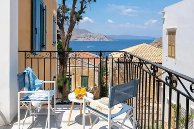 a balcony with chairs and a table with a view of the ocean at Cedrus Blue in Symi