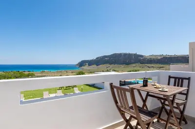 a table and chairs on a balcony with a view of the ocean at Villa Melodia, 4 Bedroom Villa with Private Pool in Líndos