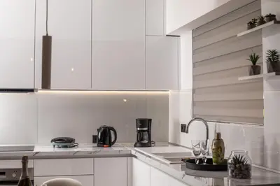 a kitchen with white cabinets and a sink with wine glasses at Rhodes Diamond luxury flat in the heart of town in Rhodes Town