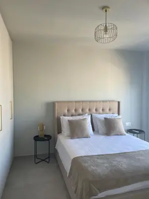 a bedroom with a large bed with white sheets and a chandelier at Serenity City Apartment in Rhodes Town